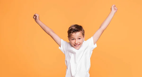 Little school boy jumping in the studio on a yellow background. Concept of happy childhood.