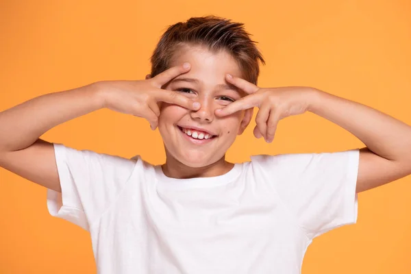 オレンジ スタジオの背景の上に立って若い感情的なハンサムな男の子 人間の感情 表情のコンセプト — ストック写真