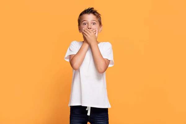 オレンジ スタジオの背景の上に立って若い感情的なハンサムな男の子 人間の感情 表情のコンセプト — ストック写真