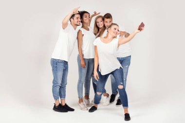 Bir grup genç insan zevk onların şirket, gülümseyerek, birlikte, cep telefonuyla selfie alarak eğleniyor.
