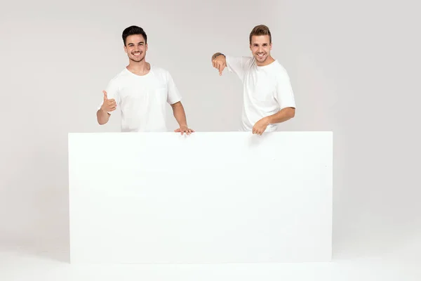 Two Young Handsome Guys Holding Blank White Banner Signboard Isolated — Stock Photo, Image