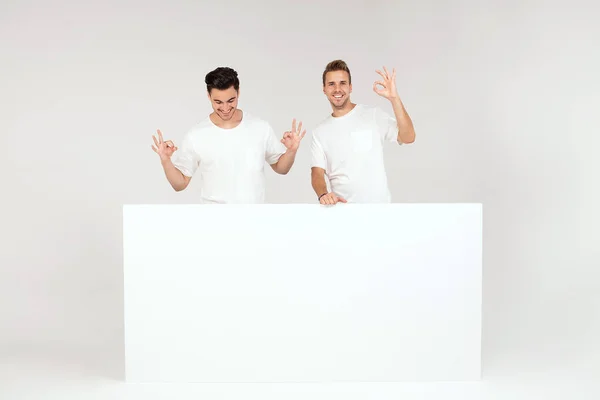 Two Young Handsome Guys Holding Blank White Banner Signboard Isolated — Stock Photo, Image