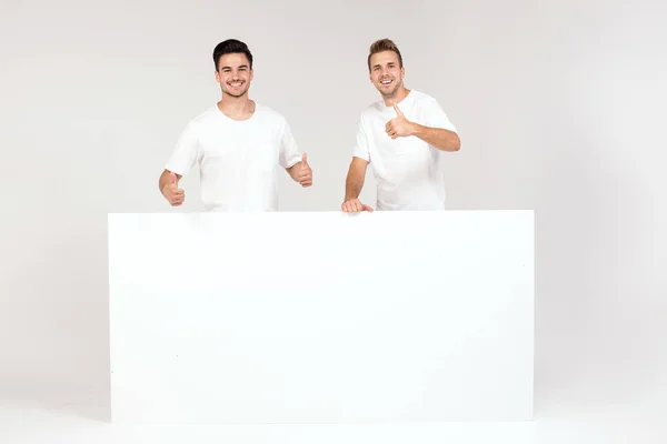 Two Young Handsome Guys Holding Blank White Banner Signboard Isolated — Stock Photo, Image
