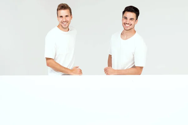 Two Young Handsome Guys Holding Blank White Banner Signboard Isolated — Stock Photo, Image