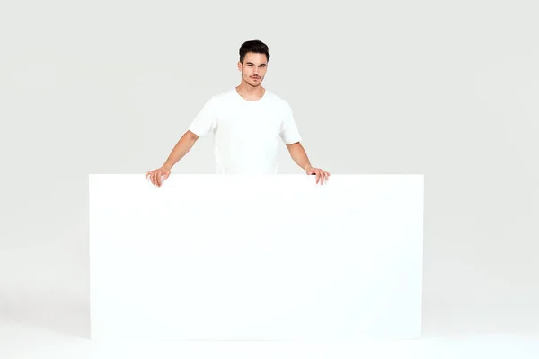年轻英俊的家伙拿着空白的白色横幅 孤立的白色演播室背景 — 图库照片
