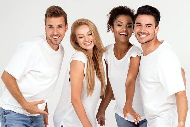 Gençlerin grup gülümseyen ve having fun birlikte, stüdyoda poz beyaz gömlek giymiş çok etnik gruptan oluşan çekici.