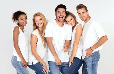 Gençlerin grup gülümseyen ve having fun birlikte, stüdyoda poz beyaz gömlek giymiş çok etnik gruptan oluşan çekici.