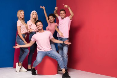 Gençlerin grup gülümseyen ve birlikte eğlenmek, renkli arka plan üzerinde poz çok etnik gruptan oluşan çekici.