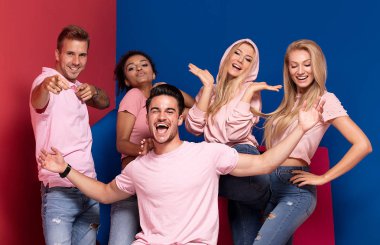 Gençlerin grup gülümseyen ve birlikte eğlenmek, renkli arka plan üzerinde poz çok etnik gruptan oluşan çekici. 