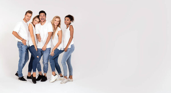 Group of young multi-ethnic attractive people wearing white shirts, smiling and having fun together, posing in studio.