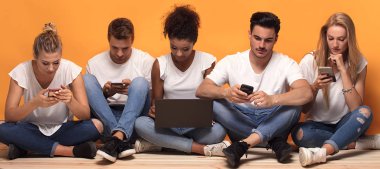Gençlerin grup birlikte vakit cep telefonları, katta oturan bakarak çok ırklı.