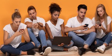 Gençlerin grup birlikte vakit cep telefonları, katta oturan bakarak çok ırklı.