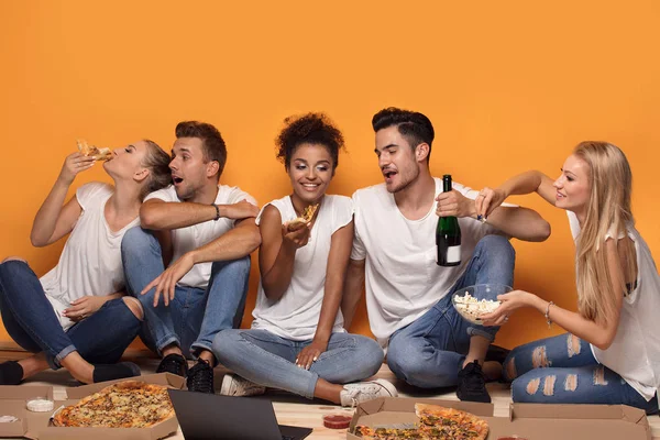 Group of multiracial friends eating pizza and having fun together.