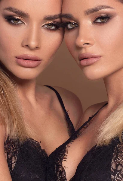 Beauty and femininity concept. Two attractive twins women in glamour makeup. Portrait photo.