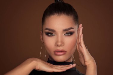 Güzellik Portresi. Glamour altın makyaj güzel kadın yüzü. Elleriyle yüzünü, yakın poz kız kameraya.
