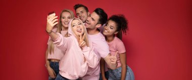 Bir grup genç insan zevk onların şirket, gülümseyerek, birlikte, cep telefonuyla selfie alarak eğleniyor.
