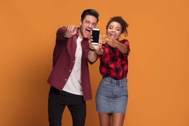 Akıllı telefon Studio'yu kullanarak rahat kıyafetler içinde güzel karışık yarış genç çift.