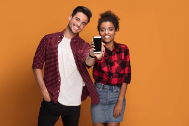 Akıllı telefon Studio'yu kullanarak rahat kıyafetler içinde güzel karışık yarış genç çift.