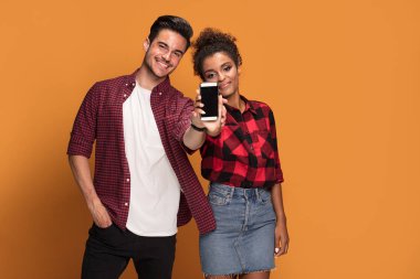 Akıllı telefon Studio'yu kullanarak rahat kıyafetler içinde güzel karışık yarış genç çift.