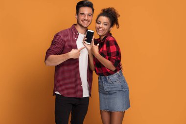 Akıllı telefon Studio'yu kullanarak rahat kıyafetler içinde güzel karışık yarış genç çift.