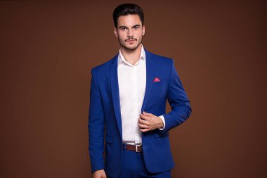 Kameraya bakarak zarif genç adam pahalı bir şık elbiseli stüdyoda, poz.