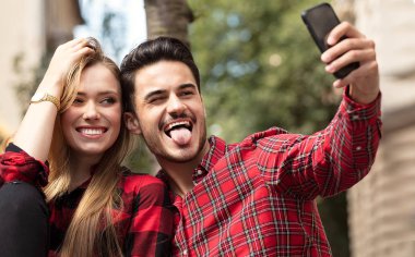 Aşk açık havada kalma çift gülümsüyor. Genç mutlu alarak selfie cep telefonuyla çift..