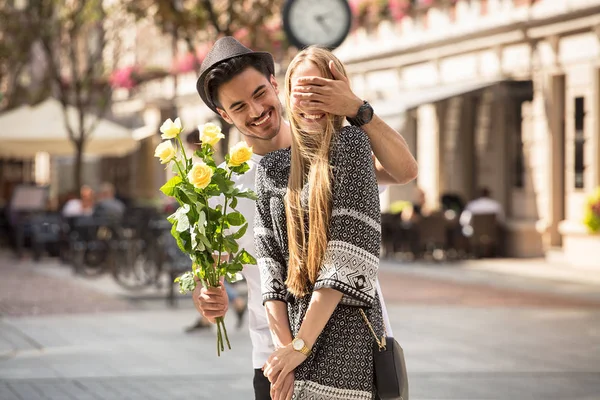 Beautiful young couple with bouquet of roses dating outdoors. Happy blonde attractive girl with handsome man.