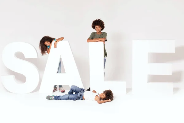 Feliz Sonrisa Tres Afro Niños Posando Con Grandes Letras Venta —  Fotos de Stock