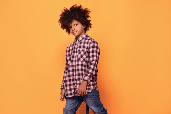 African american little man in fashionable shirt. Studio shot. Young boy posing on yellow background.