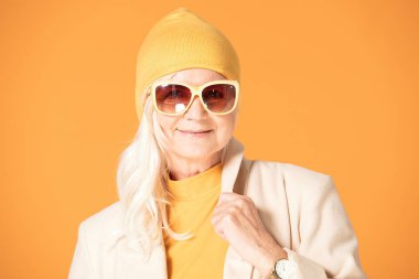 Sarı şapka ve güneş gözlüğü Olgun kadın gülümsüyor. Stüdyo vurdu.