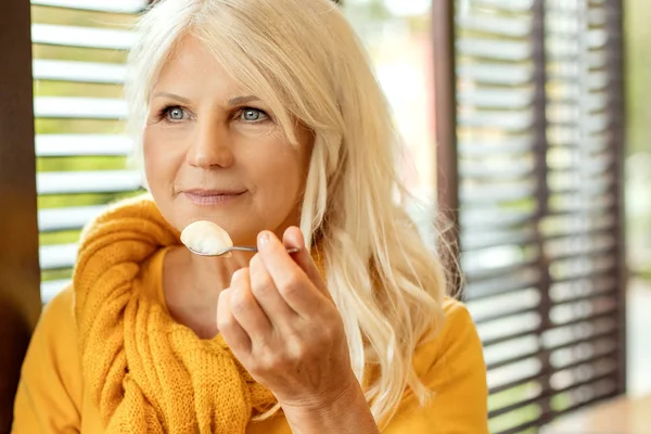 Stylish gorgeous senior woman posing indoors with mug of coffee. Elderly people, modern lifestyle, beauty and fashion concept.