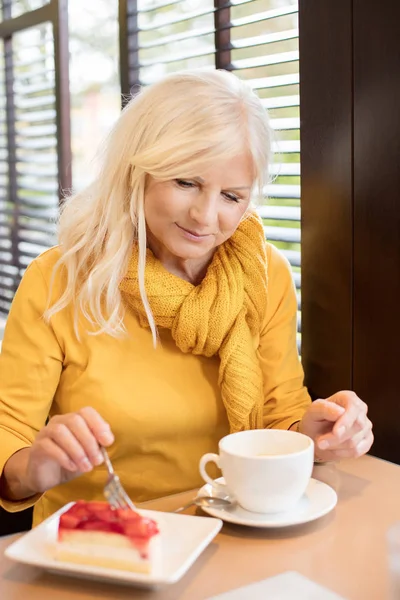 Stylish gorgeous senior woman posing indoors with mug of coffee. Elderly people, modern lifestyle, beauty and fashion concept.