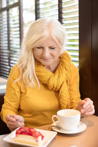 Stylish gorgeous senior woman posing indoors with mug of coffee. Elderly people, modern lifestyle, beauty and fashion concept.