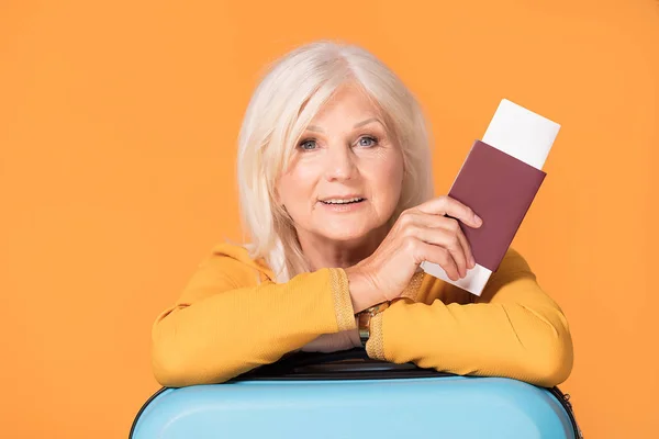 Leende senior kvinna med resväska och pass. — Stockfoto