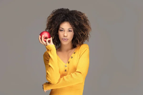 Healthy beautiful african american model with apple and open mouth looking at camera. Studio background.