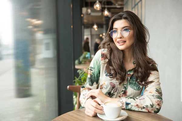 Mulher sorridente pensativo sentado na cafetaria . — Fotografia de Stock