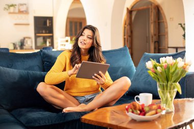 Evde tablet kullanan genç bir kız..