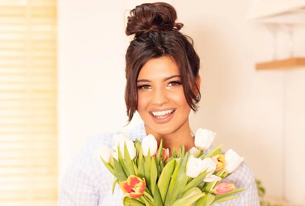 Vrouw met bloemen, glimlachend naar de camera. — Stockfoto