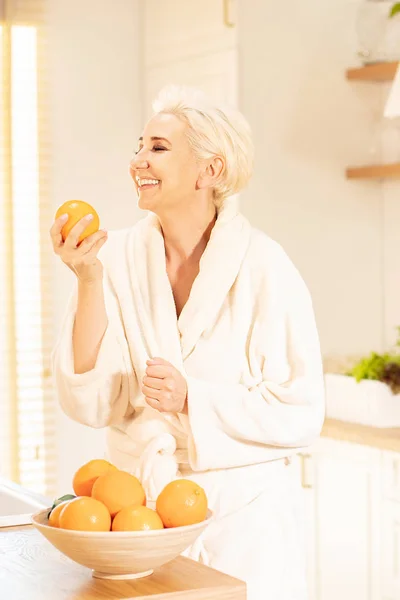 Vrolijke vrouw met verse sinaasappels in de keuken. — Stockfoto