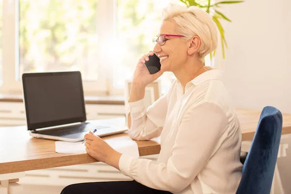 Happy businesswoman sitting at desk in office. — Stock Photo, Image