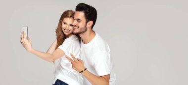 Mutlu çift cep telefonuyla selfie çekiyor.