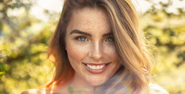 Happy girl with freckles posing in sunny garden. — Stock Photo, Image