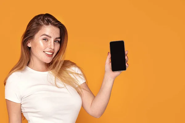 Lächelndes Mädchen zeigt Handy mit leerem Bildschirm. — Stockfoto