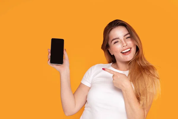 Lächelndes Mädchen zeigt Handy mit leerem Bildschirm. — Stockfoto
