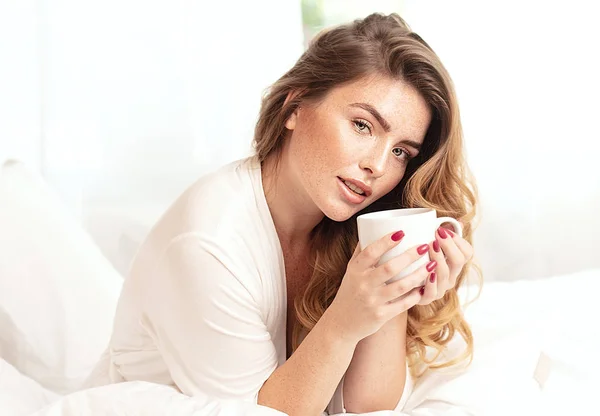 Chica pelirroja feliz sonriendo, relajándose en la cama . — Foto de Stock