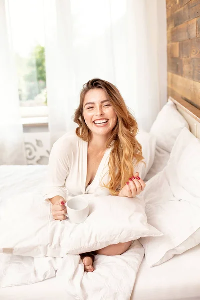 Chica pelirroja feliz sonriendo, relajándose en la cama . — Foto de Stock