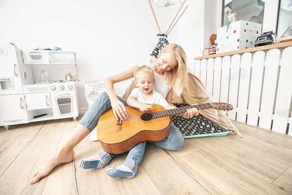 Kleine jongen spelen op gitaar met moeder . — Stockfoto