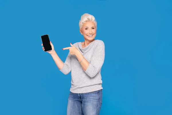 Sonriente mujer adulta sosteniendo el teléfono celular . — Foto de Stock