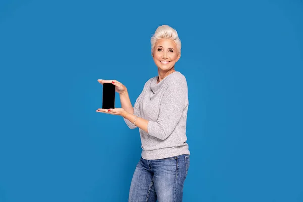 Усміхнена доросла жінка тримає мобільний телефон . — стокове фото