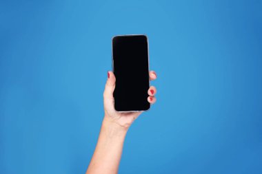 mavi arka plan üstünde hareket eden telefon ile el.